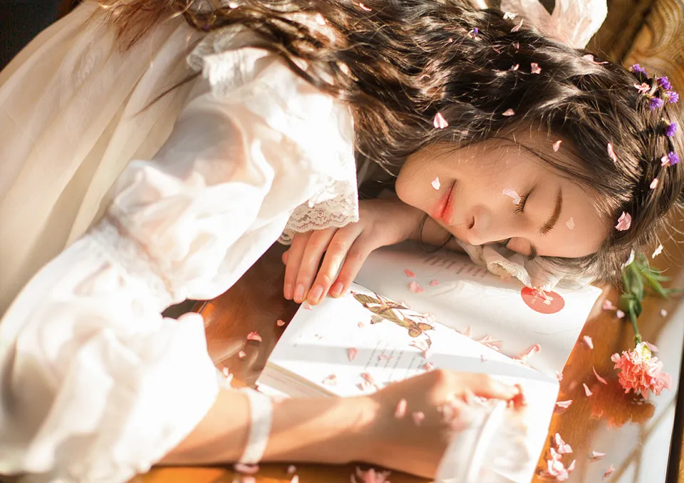 细碎花瓣点缀在少女发间和脸旁,画面柔美自然